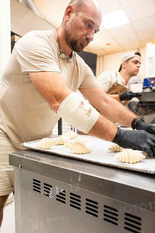 Skilled bakers work in an Italian bakery, preparing dough for fresh pastries The warm, inviting atmosphere of the kitchen highlights the art of traditional baking