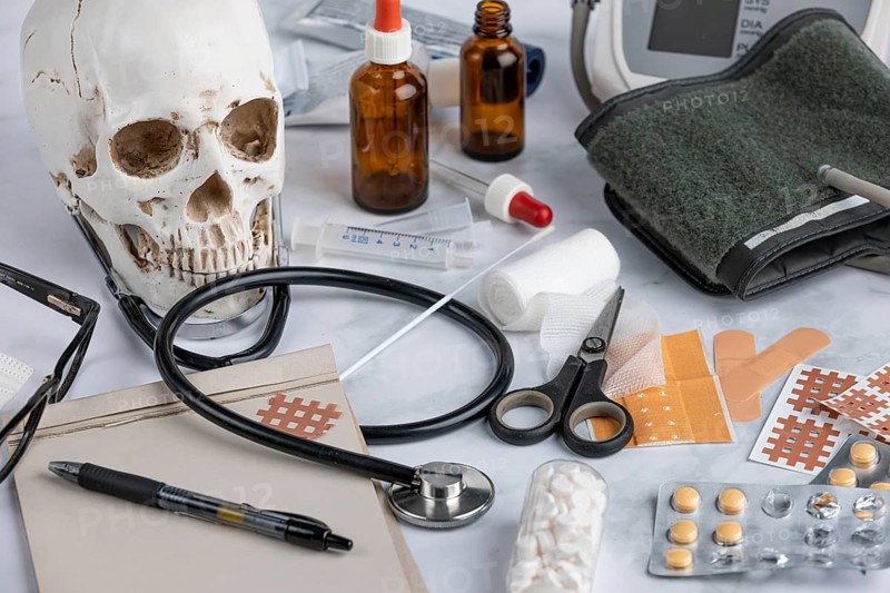 A skull and medical accessories such as a stethoscope, blood pressure gauge and tablets, clinical scene