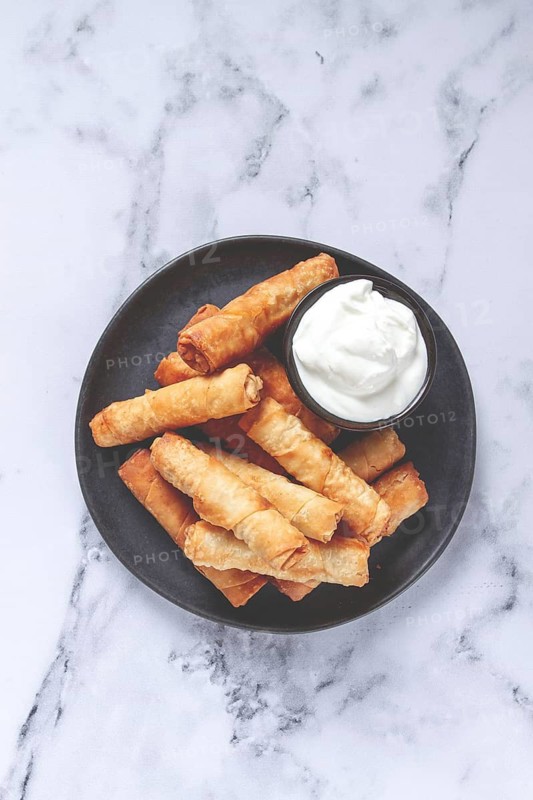 Fried spring rolls with cheese, on a plate, with cream sauce, no people