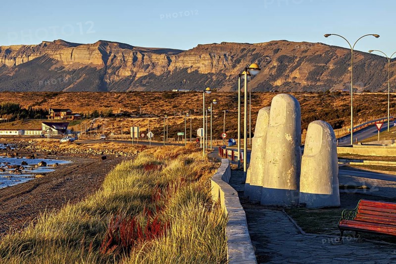 A sculpture with large fingers next to a coastal road in a mountainous landscape in the evening light, The fingers in the landscape near Puerto Natales in Patagonia Chile