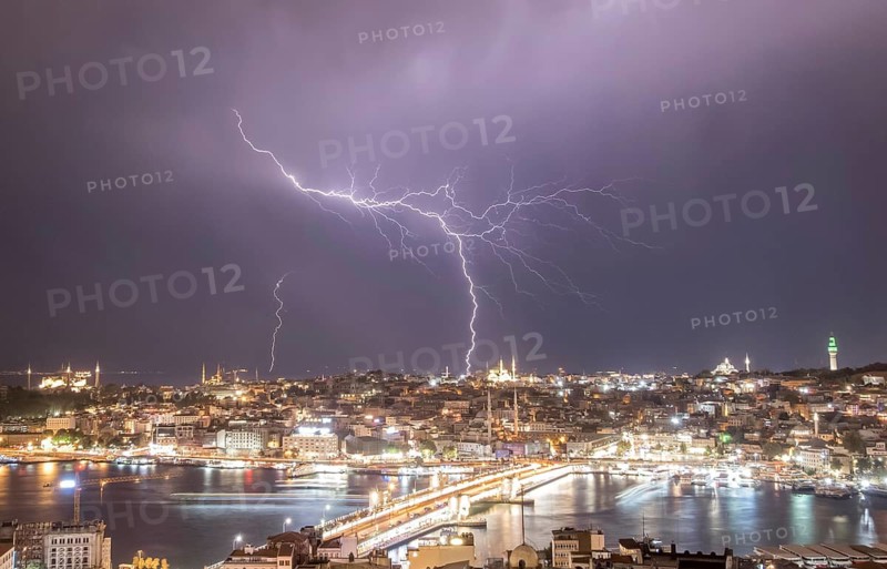 A dramatic view of Istanbul at night, illuminated by a spectacular lightning storm, showcasing the vibrant cityscape and iconic landmarks along the Bosporus