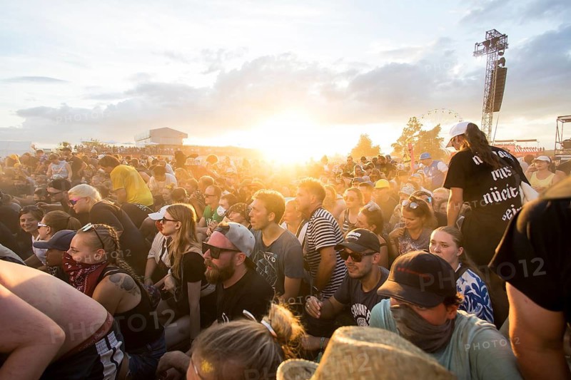 Festival visitors in front of the setting sun during the performance of the band Feine Sahne Fischfilet at the Highfield Festival on Saturday, Störmthaler See, 17.08.2024