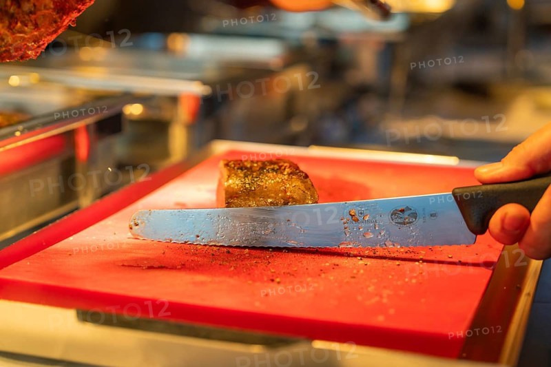 A sharp knife cuts through a perfectly cooked piece of meat on a board, Europäischer Hof, Königsbach Stein, Germany