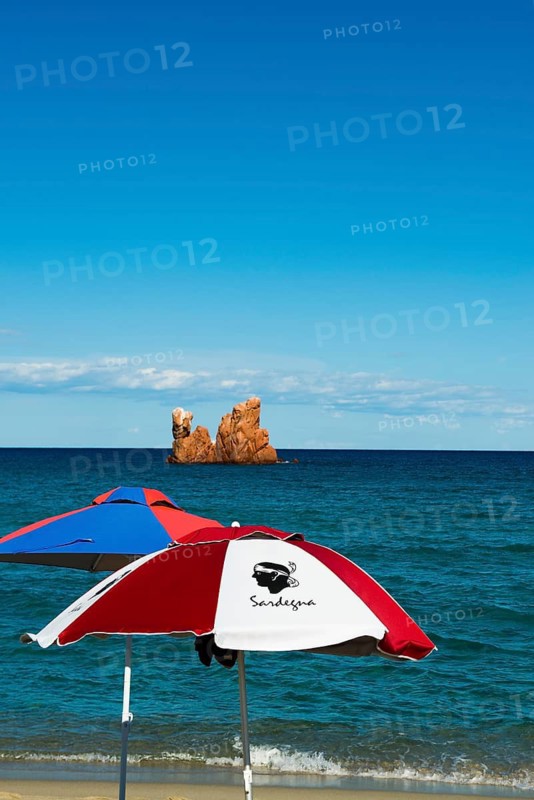 Sunshades on the beach and red rocks, Spiaggia di Cea, Tortoli, Sardinia, Italy