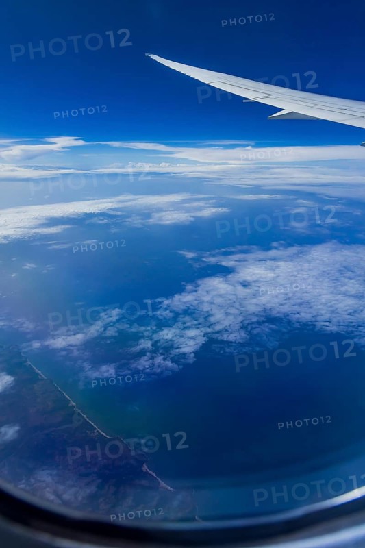 View from the aircraft window during a flight over India with the airline Etihad. Blue sky and cloud structures over the sea, wing of a Boeing 787 aircraft