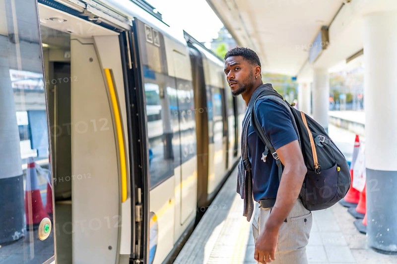 Side view photo of a young African man boarding an intercity train