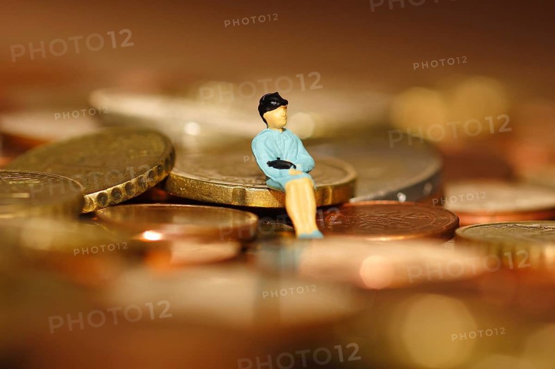 Miniature woman sitting on euro coin, North Rhine-Westphalia, Germany