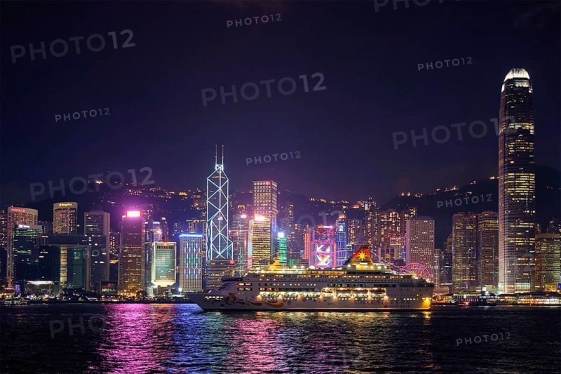 HONG KONG, CHINA, MAY 1, 2018: Hong Kong skyline cityscape downtown skyscrapers over Victoria Harbour in the evening illuminated with cruise ship. Hong Kong, China
