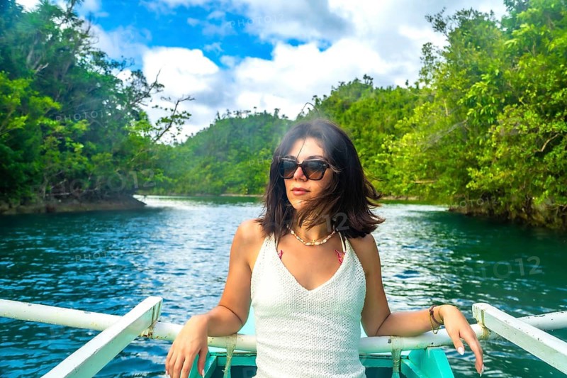 Young woman relaxing on a traditional outrigger boat, navigating the turquoise waters of sugba lagoon, surrounded by lush vegetation
