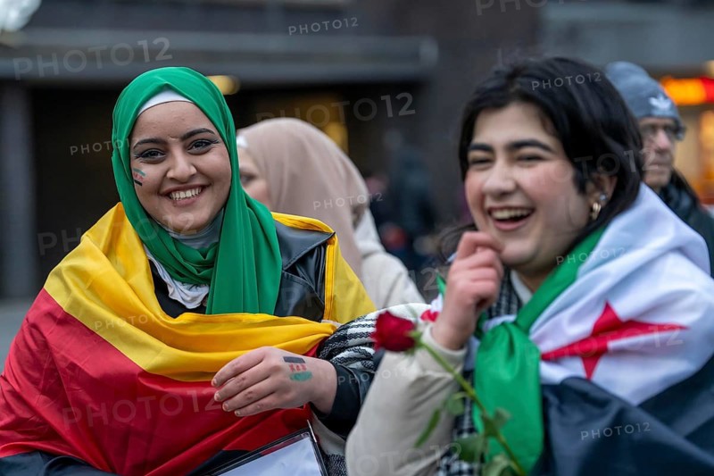 Syrian woman celebrate the end of the Assad regime after the change of power in Syria at a rally on the square in front of the main railway station in Duisburg, North Rhine-Westphalia, Germany
