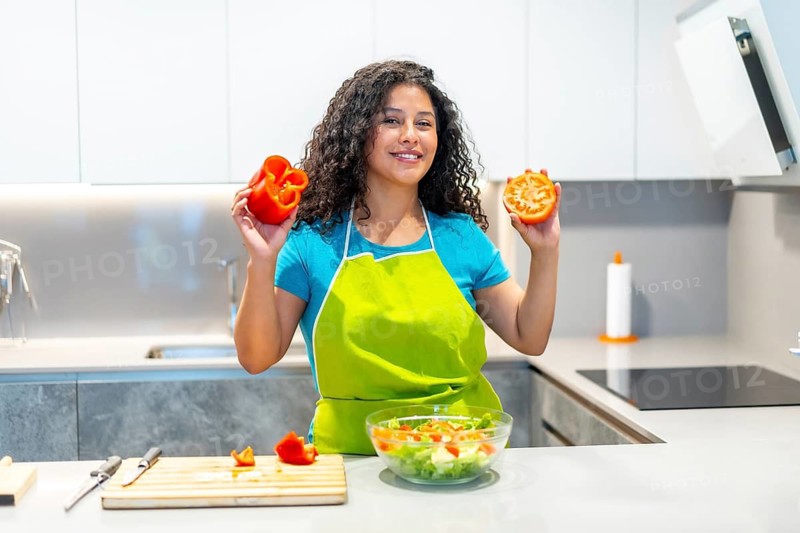Smiling latin young female blogger recording video lesson on smart phone about how to prepare healthy salad