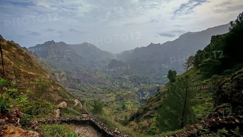 Panoramic, spectacular view over a valley with a winding path, hiking trail and mountains in the background under foggy conditions, hiking from Cova Crater through Paul Valley, Ribeira do Paul to Vila das Pombas, Santo Antao, Cabo Verde, Cape Verde, Cape Verde