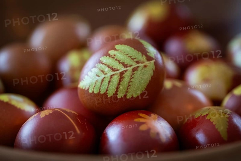 Easter eggs traditionally colored with onion skins, tights and small plants, ferns and flowers in a wooden bowl