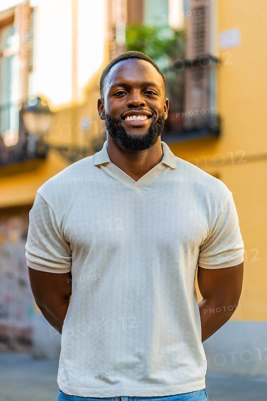 Vertical portrait of an african man with hands on back smiling at camera in the street