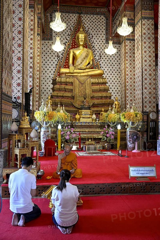 Praying in front of a Buddha statue in Wat Arun, Temple of Dawn, Bangkok, Thailand