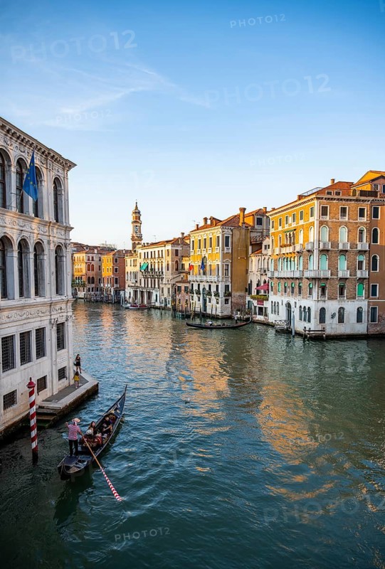 View of the Grand Canal with gondoliers at sunset, picturesque evening mood with palazzos on the canal and church tower of the Chiesa Parrocchiale dei Santi Apostoli, view from the Rialto Bridge, Venice, Veneto, Italy