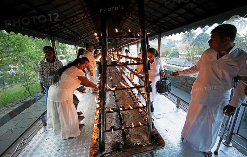 Sri Lankan pilgrims pour oil into candle holders at the Buddhist Temple of the Tooth or Sri Dalada Maligawa, Kandy, Central Province, Sri Lanka