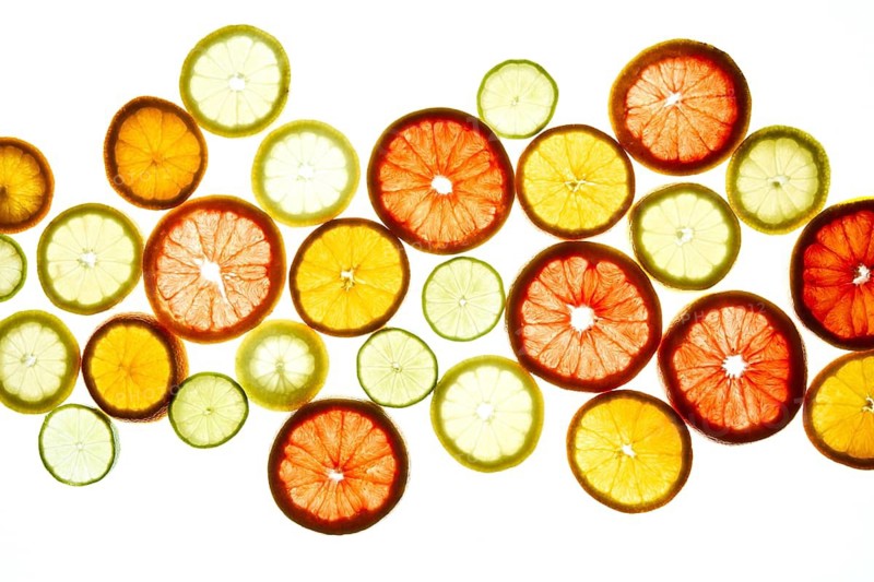 A colorful array of citrus slices, including oranges, lemons, limes, and grapefruits, displayed on a bright background. The vibrant colors create a fresh, lively feel