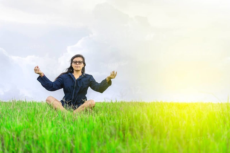 Woman meditating in the field. Relaxed woman doing yoga in the field