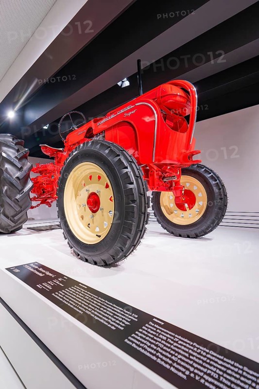 Close-up of a red vintage tractor with big tires in an exhibition, Porsche Museum, Stuttgart, Germany