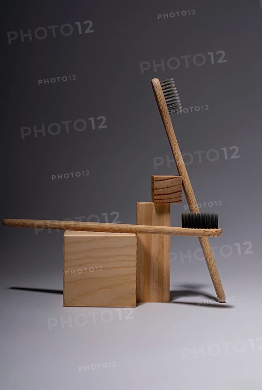 Bamboo toothbrushes artistically arranged with wooden blocks on a smooth gray surface, reflecting an eco-friendly lifestyle and minimalist aesthetic in a serene setting