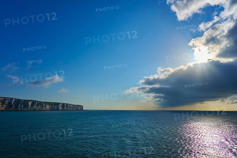 Brilliant sunlight through clouds over ocean and cliffs, shimmer on water, summer, chalk cliffs, English Channel, Dover, Kent, England, Great Britain