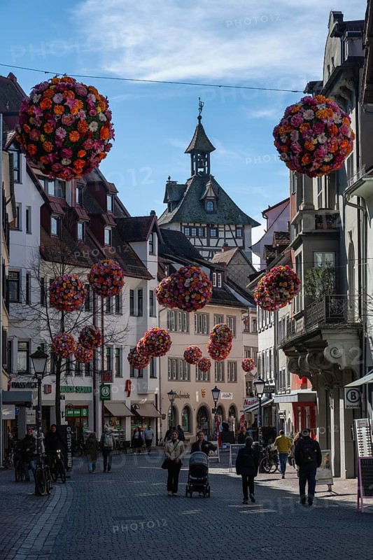 Street scene, busy pedestrian zone in the historic old town of Constance with spherical floral decorations hanging between the buildings, Konstanz district, Baden-Württemberg, Germany