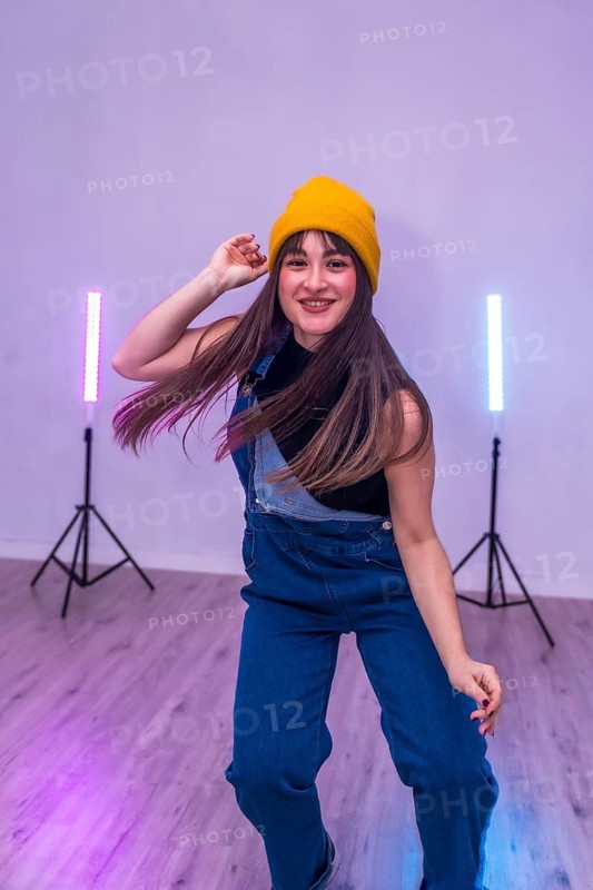 Energetic dancer showcasing her moves in a vibrant dance studio, illuminated by colorful led lights