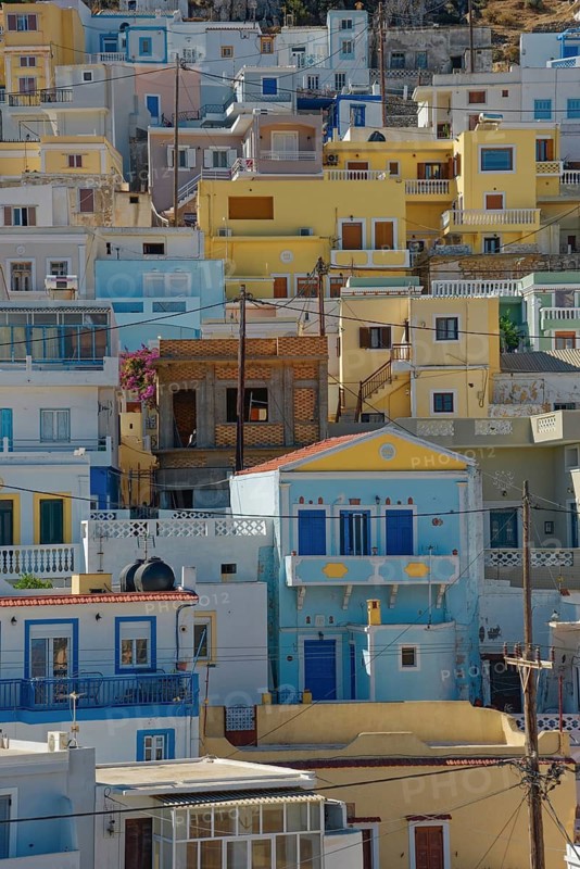 Densely built-up Mediterranean town of Menetes with pastel-coloured houses under a sunny sky, Menetes, Karpathos, Greece