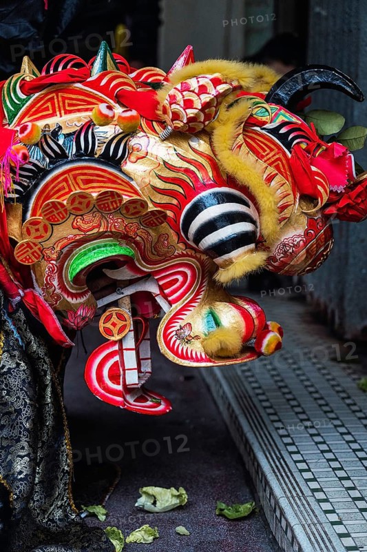 Close-up of a colorful dragon mask worn during the Chinese New Year festivities in Hong Kong. The detailed mask features red, gold, and black designs, symbolizing good luck and prosperity