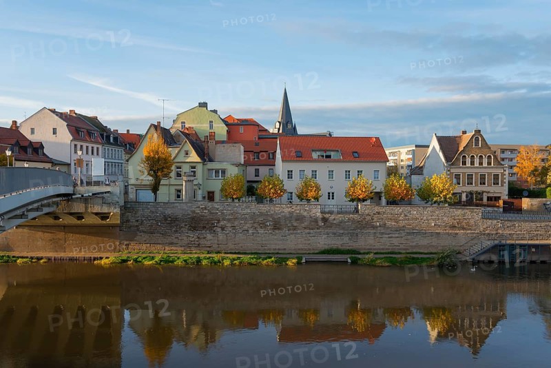Colourful buildings by the river with autumn trees reflecting in the water in the evening light, a bridge in the background, city view, Bernburg an der Saale, Saxony-Anhalt, Germany