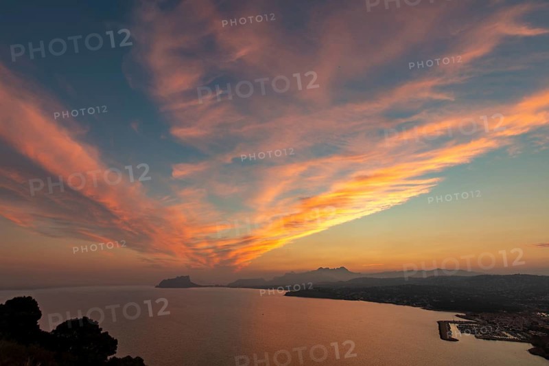 A breathtaking sunset over the Mediterranean sea at Costa Blanca, capturing vibrant colors reflecting in the water. The landscape presents a tranquil and serene setting