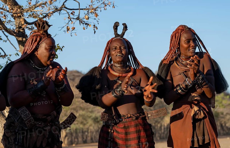 Traditional Himba woman clapping, music and dance, portraits, in the evening light, near Opuwo, Kaokoveld, Kunene, Namibia