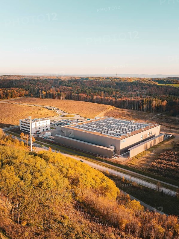 Aerial view of a factory next to woodland under a clear sky, Lindenrain industrial estate, Gechingen, Black Forest, Germany