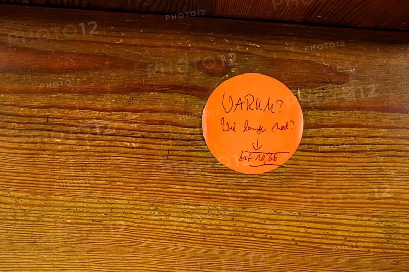 Why?, How much longer?, questions on a sticky note on a church pew with a Bible reference to Matthew 10:36