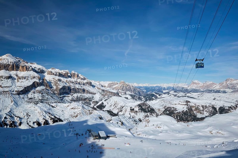 View of a ski resort piste with people skiing in Dolomites in Italy with cable car ski lift. Ski area Arabba. Arabba, Italy