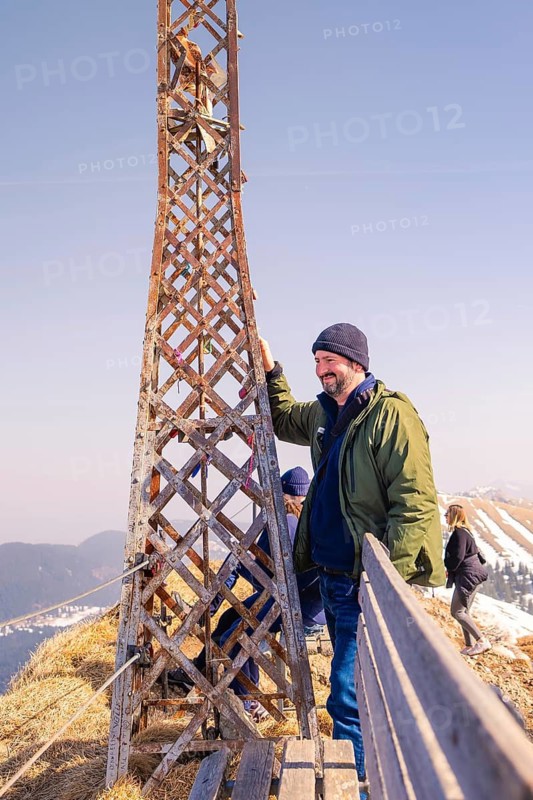 Man standing next to metal structure with a view of the winter mountain landscape, Hochgrat Mountains, Allgäu Alps, Oberreute, Germany