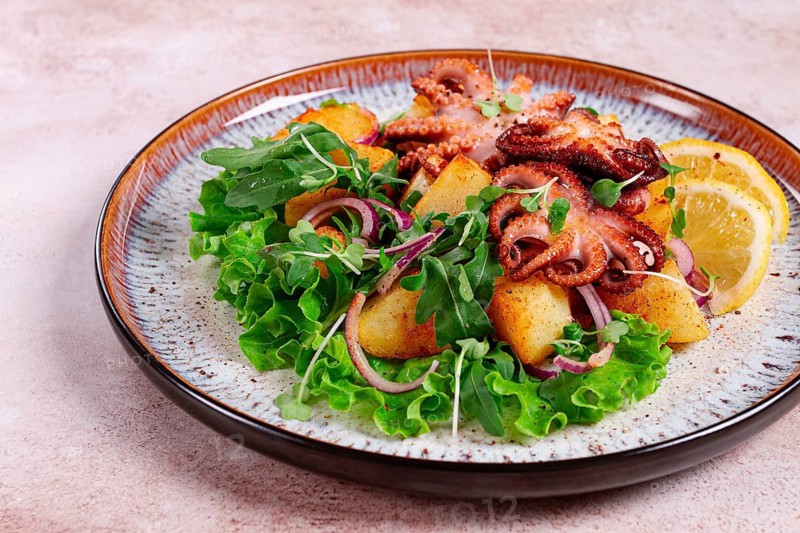 Grilled octopus with baked potatoes and fresh herbs, on a decorative plate, homemade