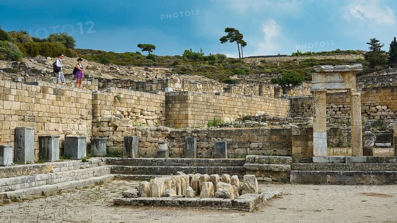 Historic ruins with several stone structures and few visitors under blue sky, ancient well house, Kamiros, Archaeological site, Ancient city, Foundation of Doric Greeks, Rhodes, Dodecanese, Greek Islands, Greece