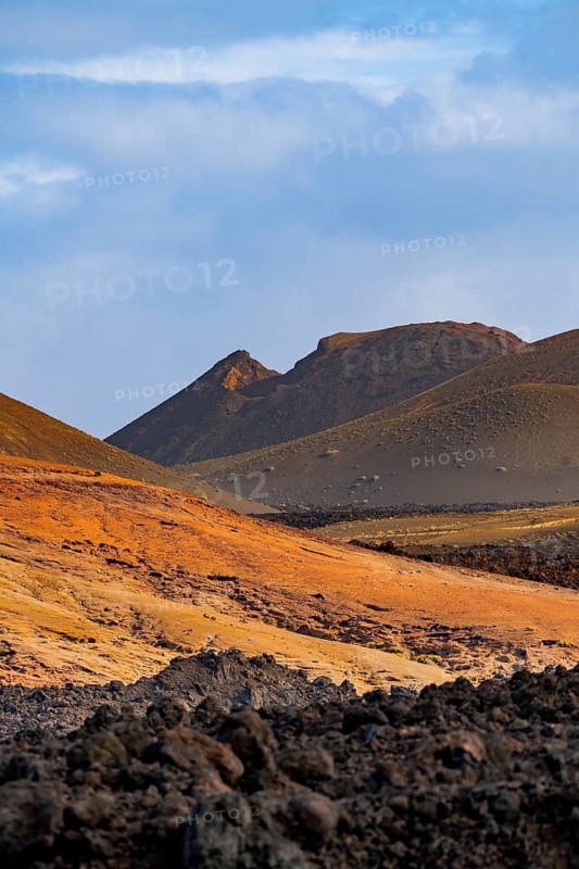 Discover the breathtaking volcanic landscape of Timanfaya National Park in Lanzarote, showcasing dramatic hills with vibrant colors under a vast blue sky in the Canary Islands