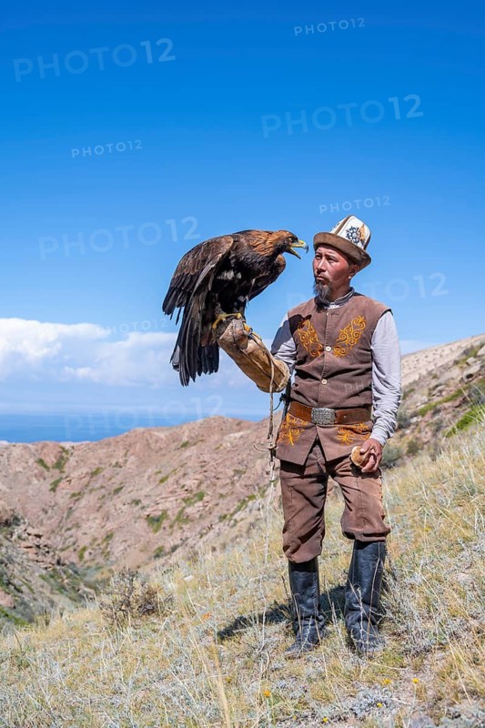 Traditional Kyrgyz eagle hunter with eagle in the mountains, near Kysyl-Suu, Kyrgyzstan