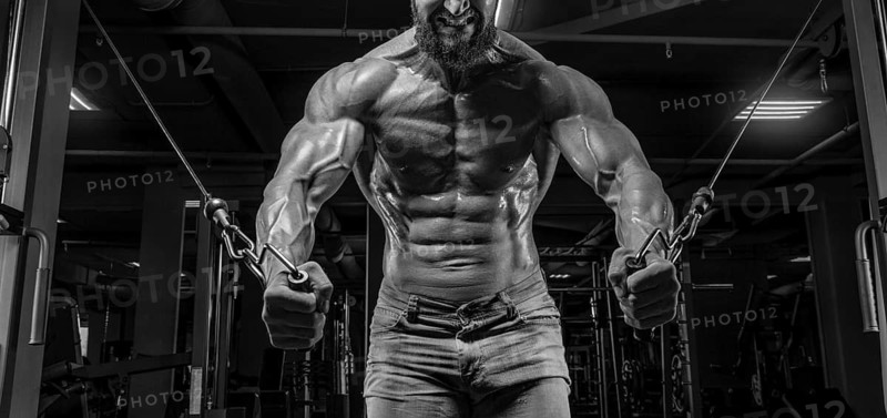 Muscular athlete training in a crossover at the gym. Pumping the torso. Fitness and bodybuilding concept.