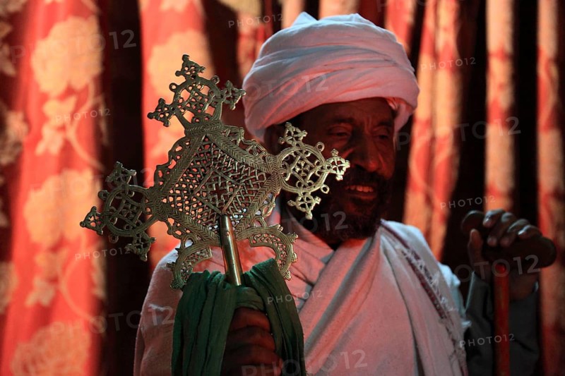 Rock churches of Lalibela, in the Church of the Cross, Bete Maskal, pilgrims, priest with cross, Ethiopia