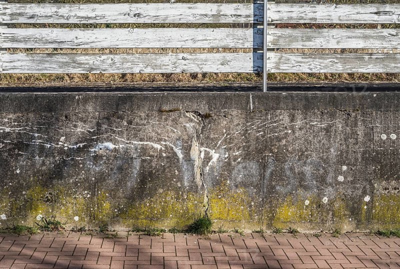 Old concrete wall with cracks, structures and a white wooden fence