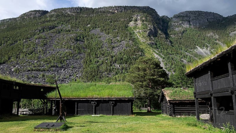 Traditional wooden houses with grass sod roofs in front of a cloudy mountain landscape, backdrop Kristin Lavranstochter film, Jørundgard Middelaldersenter, Olavsweg or Olavsleden, Sel municipality, Gudbrandsdalen, Norway