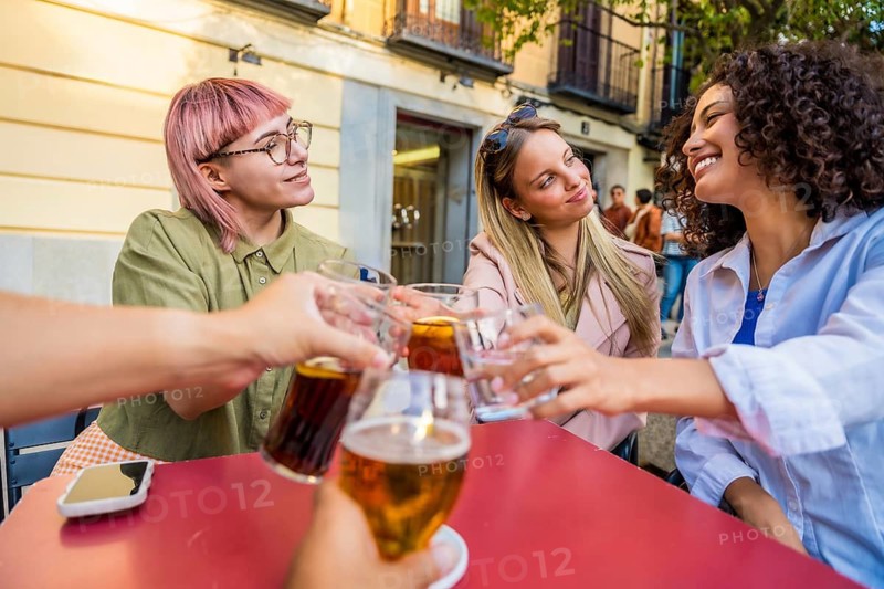 Group of diverse friends toasting with beer in an outdoor terrace at bar