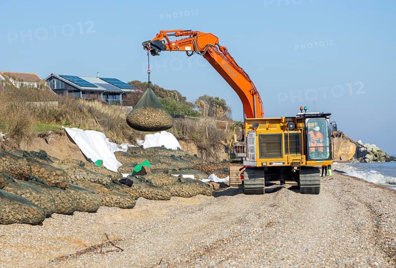 Emergency coastal defences work placing rock bags on beach to protect property, North Sea coast, Thorpeness, Suffolk, England, UK