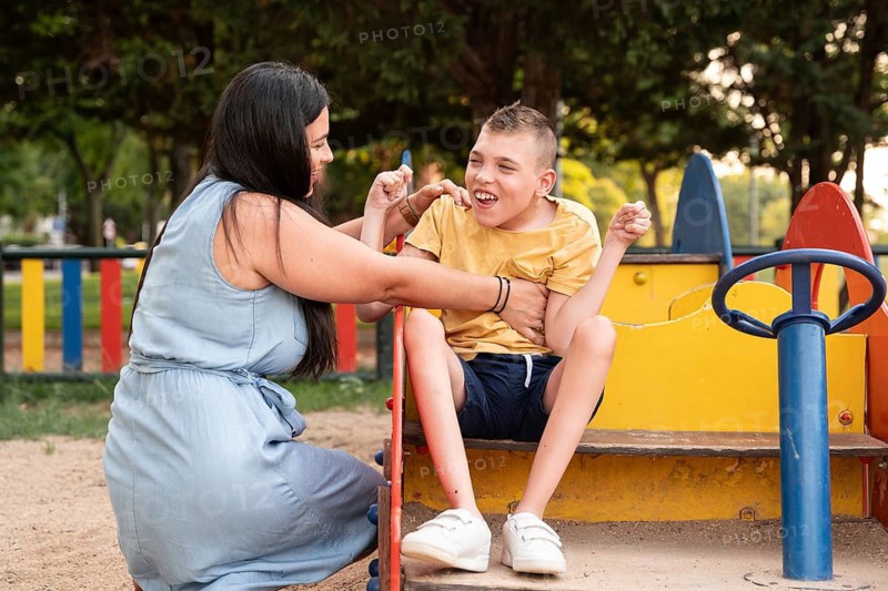 A loving mother and her son with cerebral palsy are enjoying a playful moment together at the park, fostering joy and connection in an inclusive environment