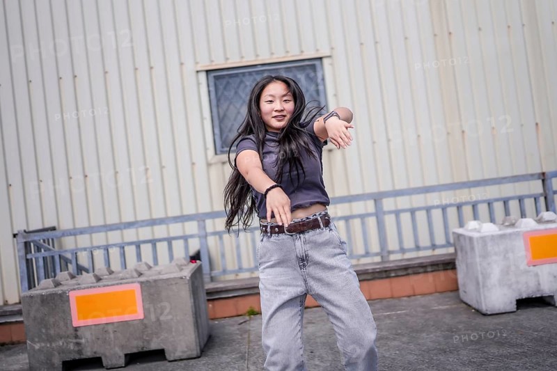 Asian young woman gesturing energetically dancing urban dance in the city