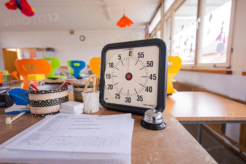 Clock and papers on an office desk in a modern room, bright windows, homework supervision, Schlehengäu Grund Schule Gechingen, Calw district, Germany